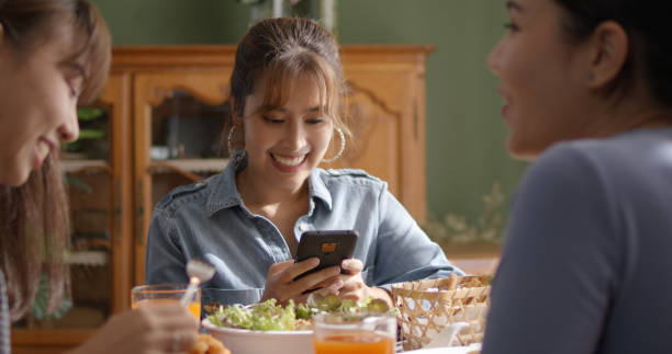 asia joven inteligente casual chica amiga del grupo se sienta en la mesa interior de la cafetería disfrutar de la risa divertida comer comida bebida almuerzo comida fiesta en la cafetería. relájese y lea el texto del correo electrónico, el comercio de  - mobile phone coffee shop group of people women fotografías e imágenes de stock