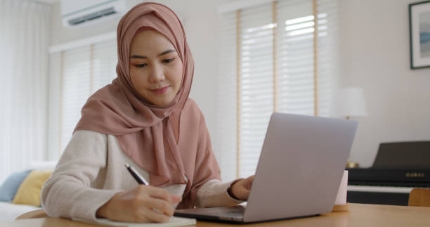 istock Young Gen Z workforce islam woman self learn MBA online class reskill upskill job at home. Asia people arab girl study relax sit at table wear hijab scarf write or typing e-mail work on digital laptop 1432161078