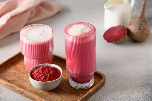 Beetroot latte or pink moon milk latte in glass cup of beetroot powder and vegan milk on gray background. Trendy healthy vegan drink. Close up.