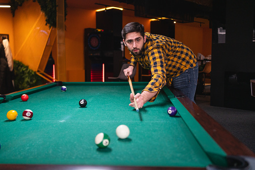 Young Caucasian man playing pool table