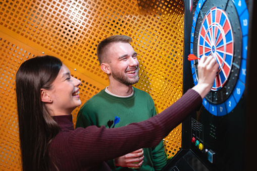 Carefree young Caucasian couple playing darts together