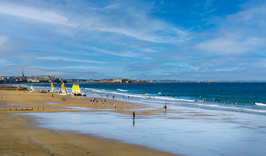 View of the beach du Sillon with people enjoying leisure and water activities, with the medieval town of Saint Malo in the background.