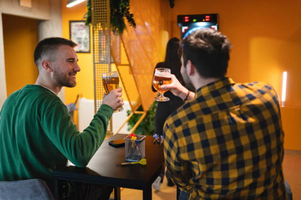 kaukasische freunde spielen darts und trinken bier - beer dartboard sport pub stock-fotos und bilder