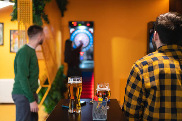 kaukasische freunde spielen darts und trinken bier - beer dartboard sport pub stock-fotos und bilder