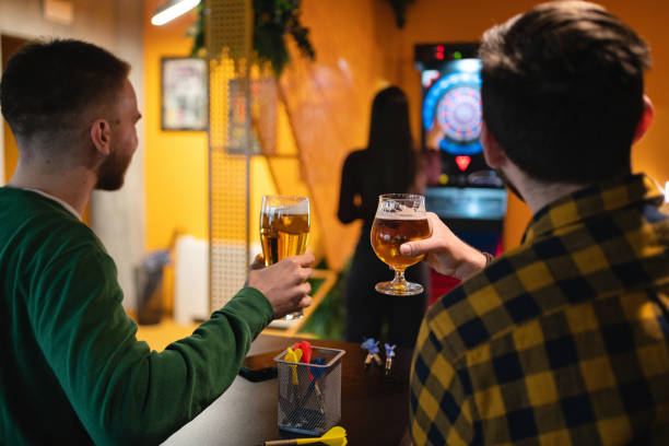 kaukasische freunde spielen darts und trinken bier - beer dartboard sport pub stock-fotos und bilder