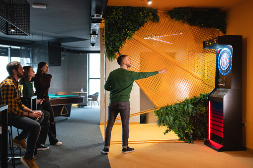 Group of Caucasian male and female friends playing darts