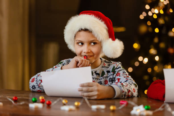 istock A black boy write letter for Santa near a festively decorated Christmas tree 1432167893