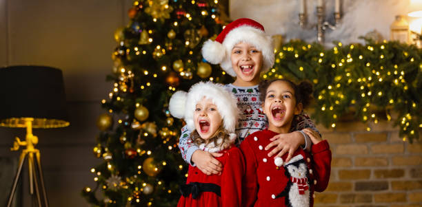 los niños cantan una canción de pie junto a la chimenea en nochebuena - carousel merry go round child african descent fotografías e imágenes de stock