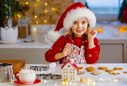 The child helps to prepare ginger cookies for the happy Christmas holiday.