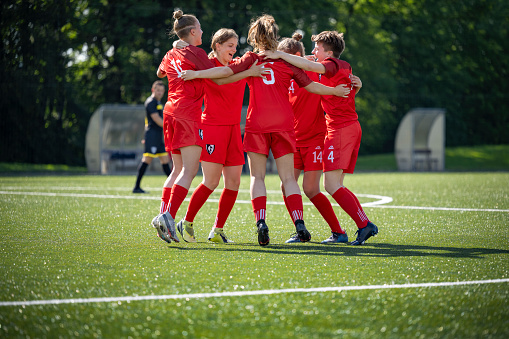 Female football players celebrating during football match on pitch.