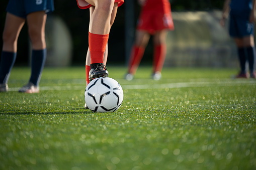 Low section of female football player with ball at soccer field.