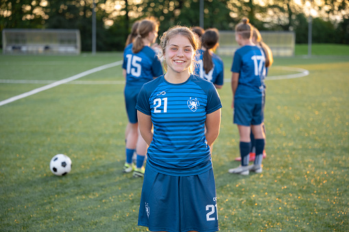 Portrait of smiling female football player standing on ground.