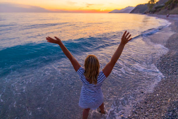 istock Woman having fun in waves at beach during sunset in summer 1432179462