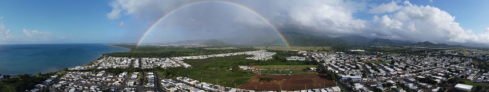 A panorama view of a beautiful town with a sea and rainbow on a sunny day