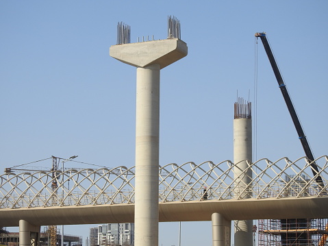Giza, Egypt, July 25 2022: Giza Egyptian overhead transportation system monorail construction site with concrete and steel columns and cranes in 26th of July axis road in 6th October city, selective focus