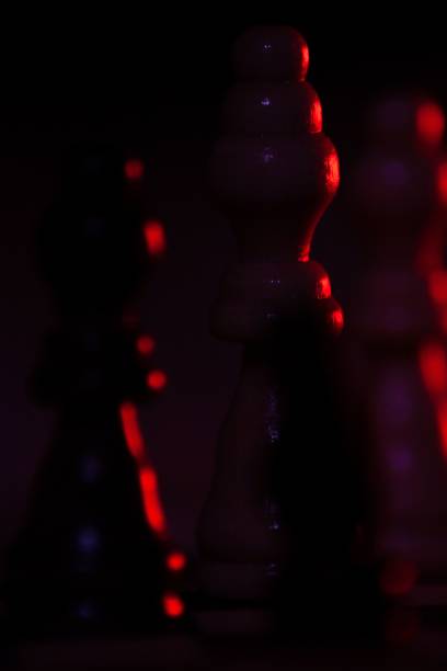 istock Vertical closeup of chess pieces in the darkness illuminated by red light. 1432189924