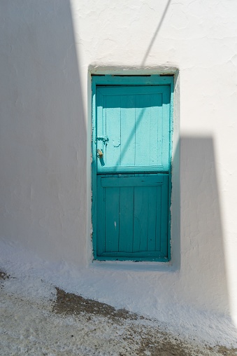 A vertical shot of a locked blue door with a metal padlock in the Cyclades, Greek Islands