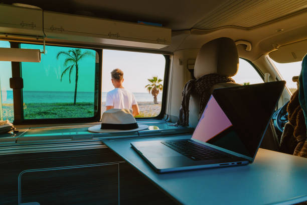 istock Close-up of laptop in campervan while man standing on beach during summer 1432192673