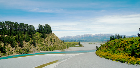 The spectacular Waimakariri River funnelling through the Waimakariri Gorge in the Canterbury Region of New Zealand's South Island. In the distance we see the snowcapped peaks of the Southern Alps