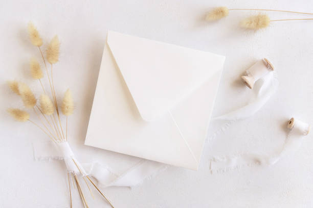 istock Square envelope near silk ribbons and dried hare's tail grass top view on white, boho mockup 1432194661