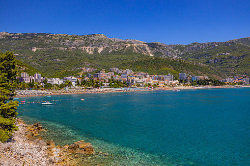 Beautiful view of coastal town with blue sea against mountains under clear sky