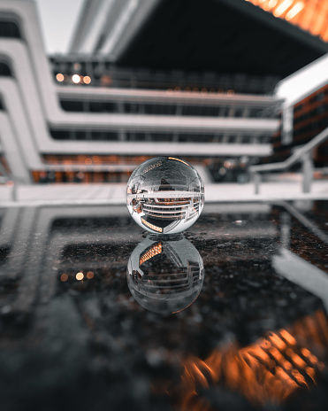 A Lensball lying in a puddle in front of a modern building in vienna (university of economics)