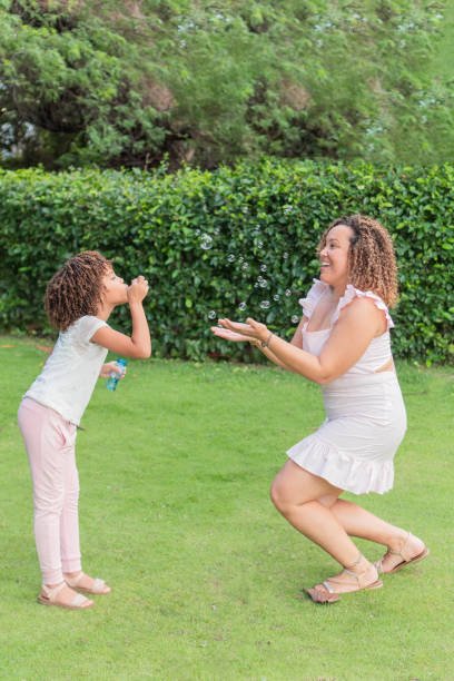 istock Latin Mother and daughter playing with bubbles in a park. 1432198826