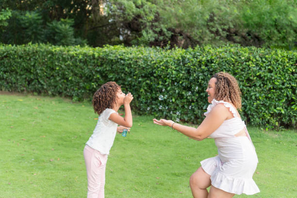 istock Mother and daughter playing with bubbles in a park. 1432198903