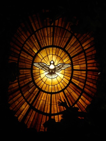 A vertical view of the dove of the Holy Spirit on the stained glass in St. Peter's Basilica