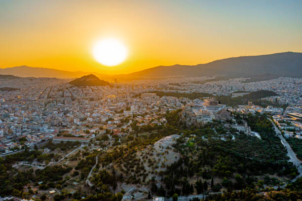 Scenic view of sun setting over cityscape and mountains against sky in summer