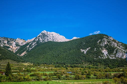 A beautiful scene of Pedraforca mountain on grass fields under blue sky, Catalonia, Spain