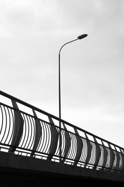 istock Long metal road fence with a tall street lamp under light sky 1432200173