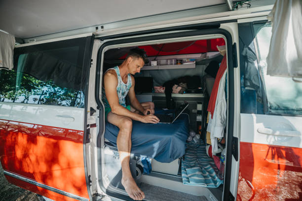 istock Tourist using laptop while sitting in campervan at beach during vacation 1432203422