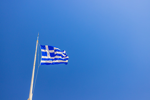 Low angle view of Greek flag waving against clear blue sky during sunny day