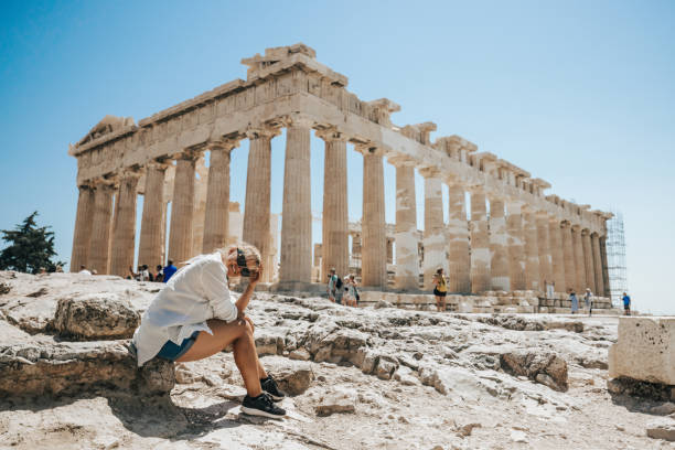 donna sorridente seduta al tempio del partenone contro il cielo limpido - clear sky acropolis athens greece greece foto e immagini stock