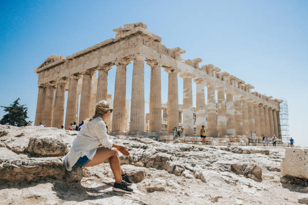 donna che si rilassa mentre guarda il tempio del partenone contro il cielo limpido - architecture past ancient man made structure foto e immagini stock