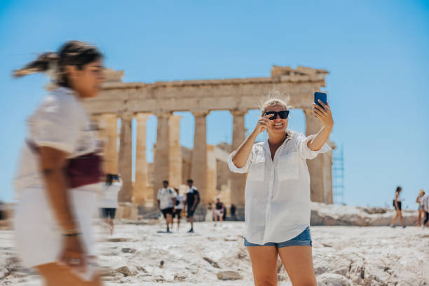 istock Smiling influencer blogging through smart phone while exploring Parthenon temple 1432205796