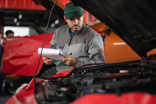 istock Automobile mechanic man writing to the clipboard checking car damage broken part condition. diagnostic and repairing vehicle at garage automotive, Concepts of car care check and full services 1432205815