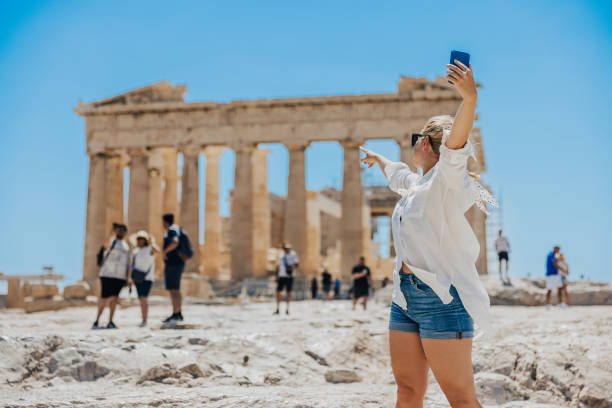 istock Female blogger pointing at Parthenon temple while vlogging on smart phone 1432205917