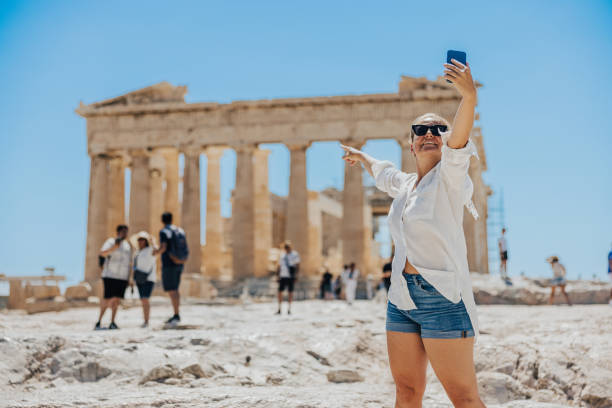 istock Smiling blogger pointing at Parthenon temple while vlogging on smart phone 1432206143