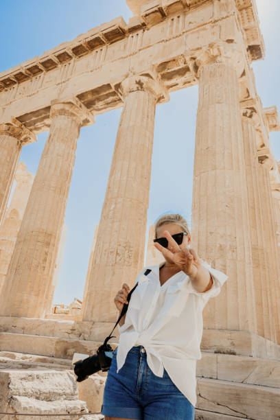 istock Woman with camera gesturing while exploring Parthenon temple against clear sky 1432207182