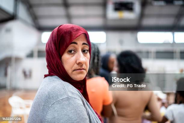 Portrait Of A Mature Woman Wearing Hijab Waiting In Line At A Community Center Stock Photo - Download Image Now