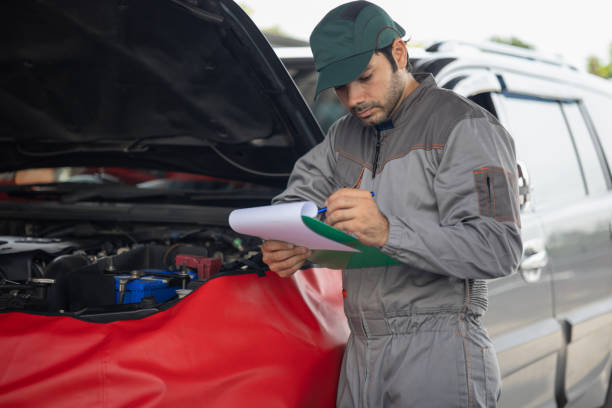 istock Automobile mechanic man writing to the clipboard checking car damage broken part condition. diagnostic and repairing vehicle at garage automotive, Concepts of car care check and full services 1432207855
