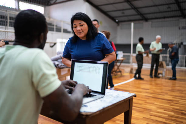 Volunteer talking with a refugee woman while using the laptop at a refugee sheltering Volunteer talking with a refugee woman while using the laptop at a refugee sheltering emergency shelter stock pictures, royalty-free photos & images