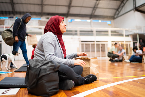 Refugee woman wearing hijab praying in a sheltering