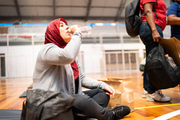 istock Refugee woman wearing hijab drinking water in a sheltering 1432207950