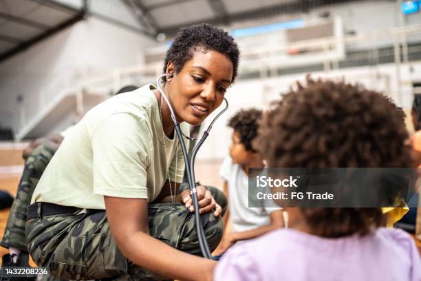 Army Doctor Examining Refugee Children At A Community Center Stock Photo - Download Image Now