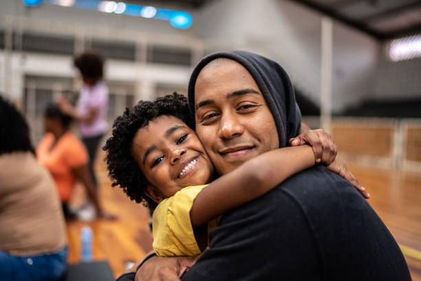 retrato de padre e hija abrazándose en un centro comunitario - take shelter fotografías e imágenes de stock