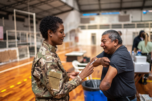 Soldier vaccinating a disabled mature man at a community center