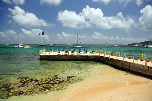 Marigot, Collectivity of Saint Martin / Collectivité de Saint-Martin, French Caribbean: sand and beach pier with deckchairs and the French flag - Marigot bay